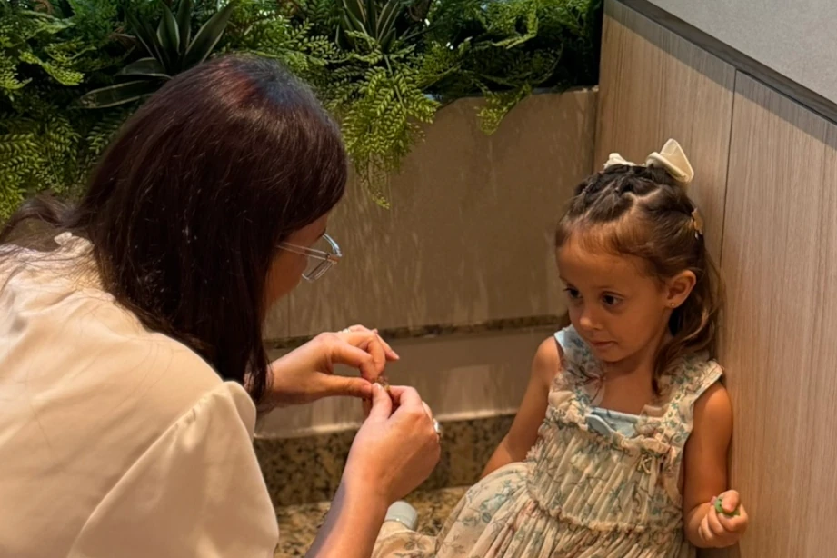 Médica agachada na altura dos olhos tentando estabelecer confiança com uma criança com expressão de concentração.