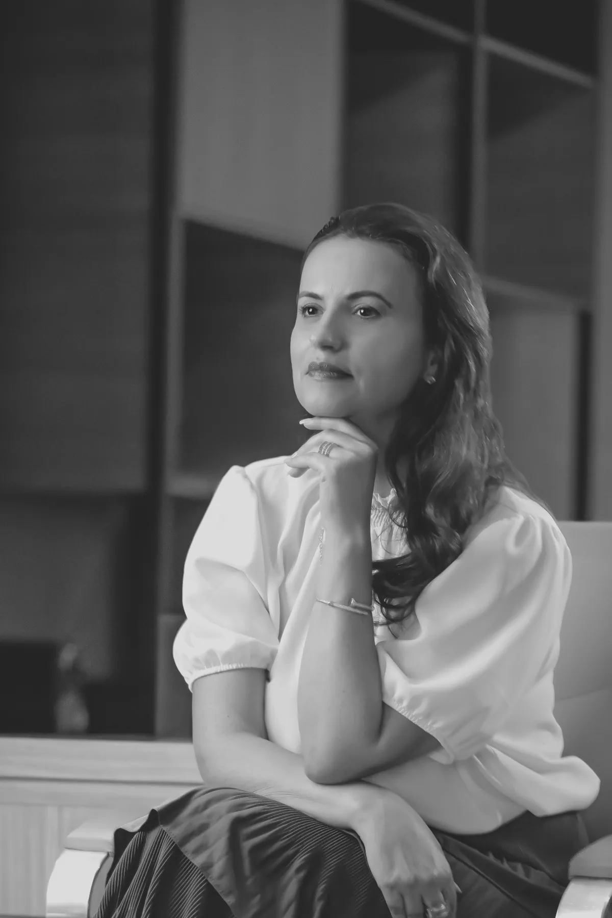 Doutora Flávia com braços cruzados e mão sob o queixo.